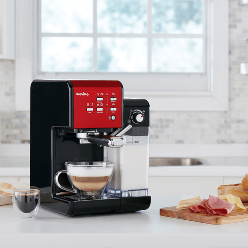 espressor breville prima latte 2 rosu pe masa langa mic dejun