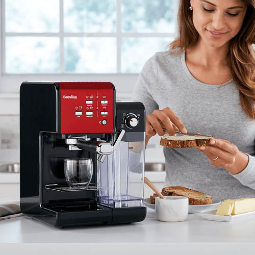 femeie pregatind sandvis langa espressor breville rosu